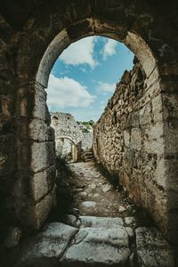 Old ruins against sky seen through arch