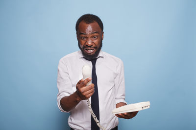 Portrait of young man standing against blue background