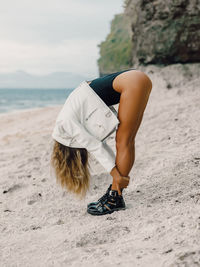 Low section of woman standing on sand at beach