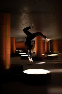 Upside down image of woman jumping in illuminated garage