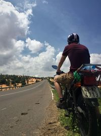 Rear view of man riding motorcycle on road against sky