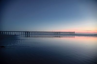 Pier over sea against clear sky during sunset