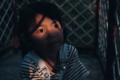 Girl looking away through fence