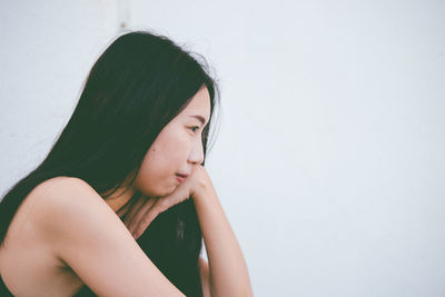 Portrait of a young woman looking away against wall