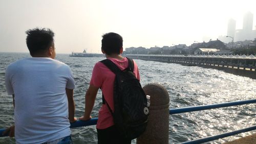 Rear view of two people standing against clear sky