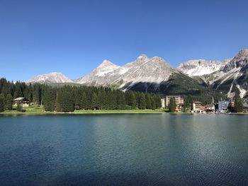 Scenic view of lake and mountains against clear blue sky