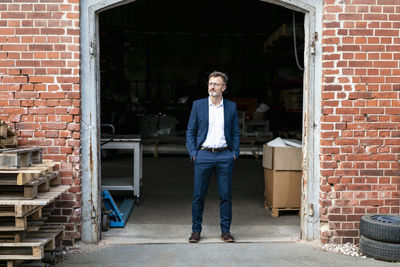 Businessman standing at old warehouse looking away