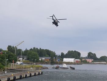 Helicopter flying over river against sky