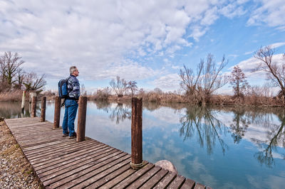 Man standing by lake against sky