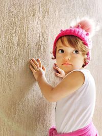 Portrait of cute girl looking away while standing against pink wall
