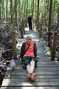 Full length portrait of woman sitting in forest