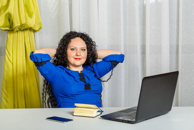 Young woman using phone while sitting on table