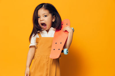 Portrait of young woman standing against yellow background