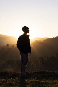 Side view of man standing on landscape at sunset