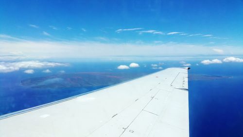 Airplane flying over landscape against blue sky