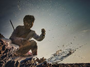 Reflection of boy in sea during sunset