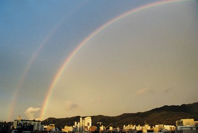 Scenic view of rainbow over town against sky