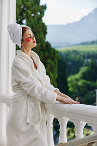 Young woman looking at camera while standing against railing