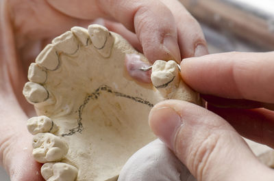 Cropped hands of person working on dentures
