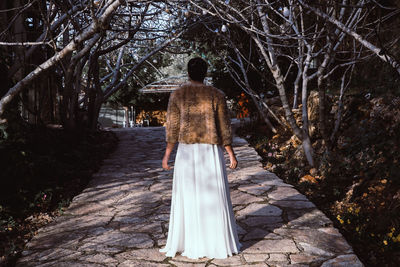 Rear view of woman standing on bare trees