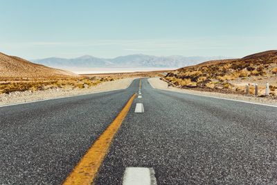 Empty road amidst desert against clear sky