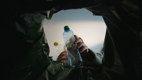 Woman throwing a plastic bottle into a trash bin. bottom view from the trash bin. eco concept 