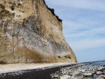 Rock formations on beach against sky