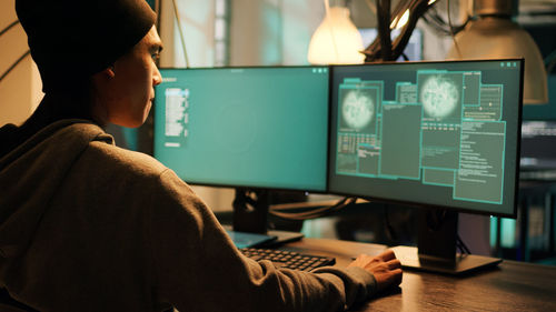 Rear view of woman using laptop in office