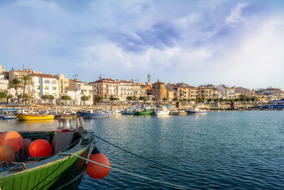 Boats moored on river by buildings in city against sky