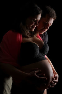 Midsection of couple against black background