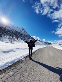 Rear view of person walking on snowcapped mountain against sky