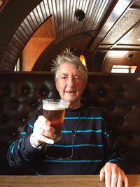 Portrait of senior man with beer glass sitting in bar