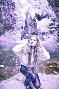 Portrait of beautiful woman standing against waterfall