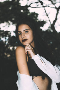 Portrait of smiling young woman standing against tree