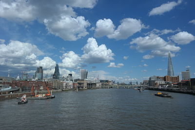 View of city at waterfront against cloudy sky