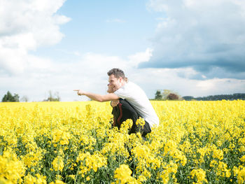 Woman piggybacking friend while standing on oilseed rape field