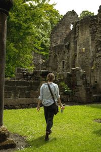 Full length rear view of senior man walking on grass