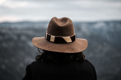 Rear view of woman wearing hat standing against sky