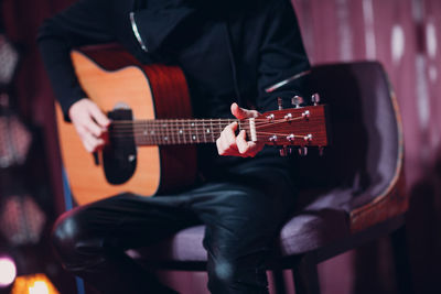 Midsection of musician playing guitar