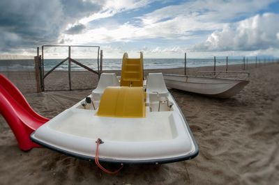 Deck chairs on beach against sky