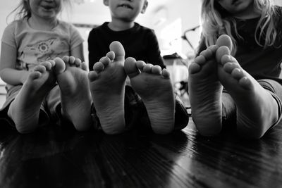 Low section of siblings sitting on floor at home