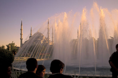 Rear view of people at fountain in city