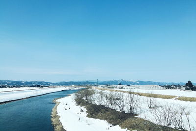 Snow covered landscape against blue sky