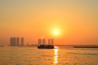 Scenic view of sea and buildings against sky during sunset