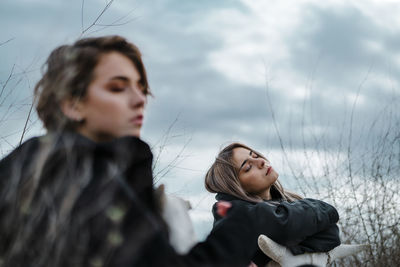 Portrait of young woman looking away against sky