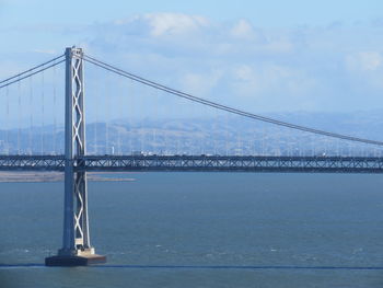 Bay bridge over sea against sky on sunny day