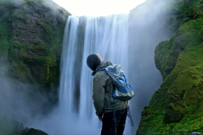 Man standing against skogafoss waterfalls