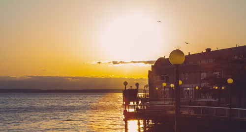 Silhouette of pier and water as sun sets in background