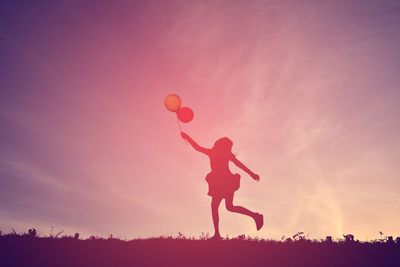 Silhouette girl playing with balloons on field against sky during sunset