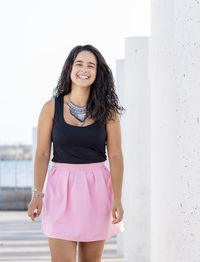 Beautiful young woman standing against pink wall